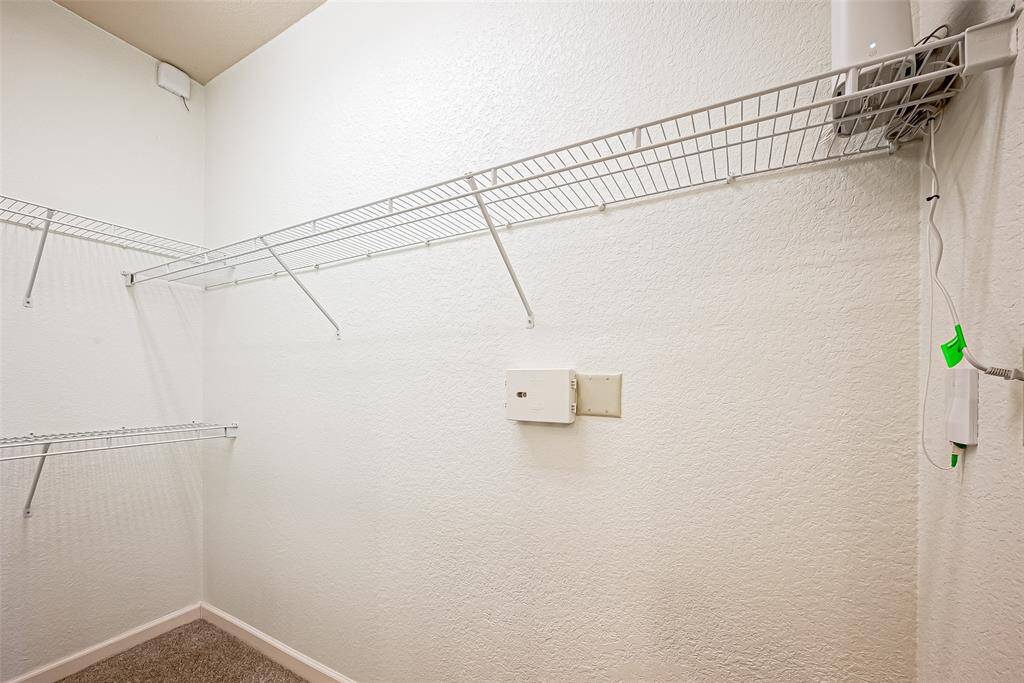 This is a walk-in closet with white wire shelving on the walls, providing extra storage space.