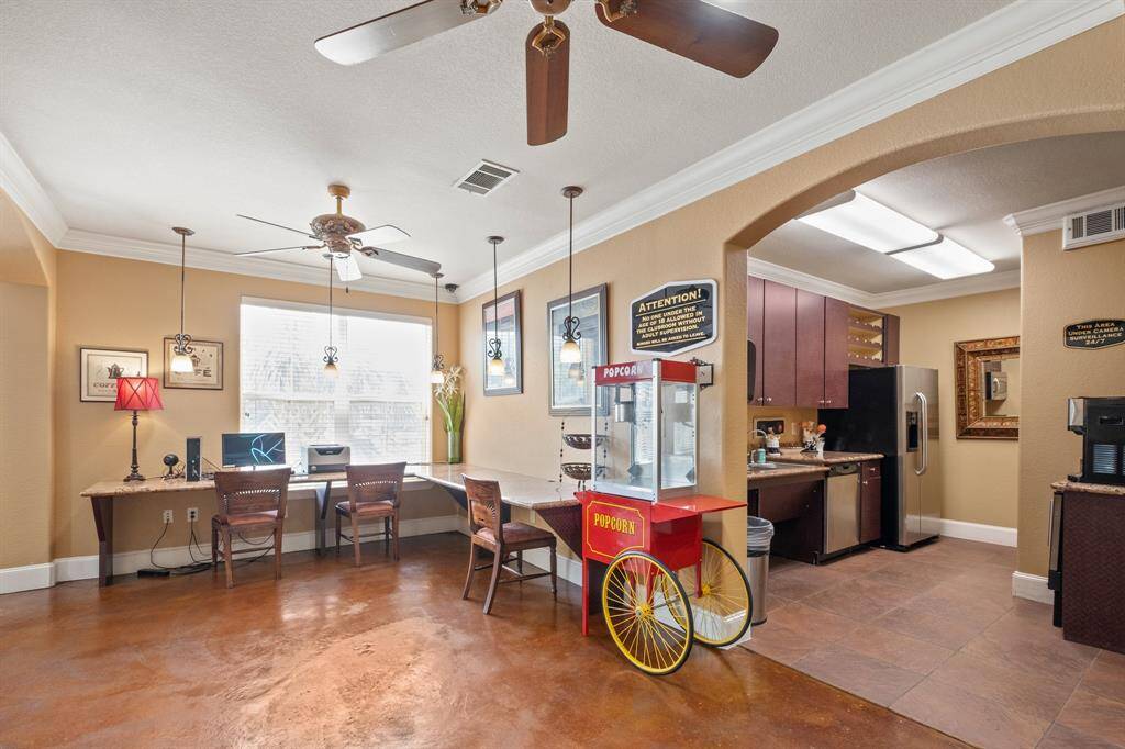 The clubhouse has a cozy seating area with desks. The adjacent kitchen area has modern appliances and sleek cabinetry, perfect for entertaining or casual gatherings.