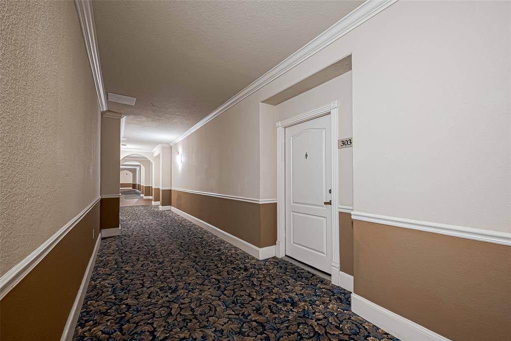 Well-lit apartment hallway with classic patterned carpeting.