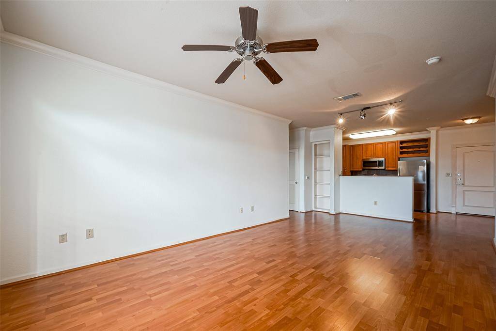 View of living room to modern kitchen featuring stainless steel appliances and ample cabinetry.