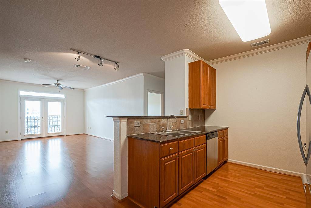 This photo showcases a bright, open-concept living space with laminate floors and a ceiling fan.