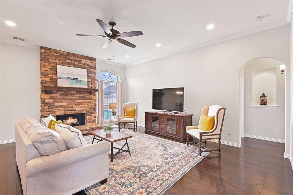 At the heart of the home, this inviting family room is anchored by a stacked stone gas log fireplace alongside of a palladium arched window with picturesque pool views. This space also boasts a ceiling fan, recessed lighting, crown molding, fresh paint, and warm-toned wood floors.