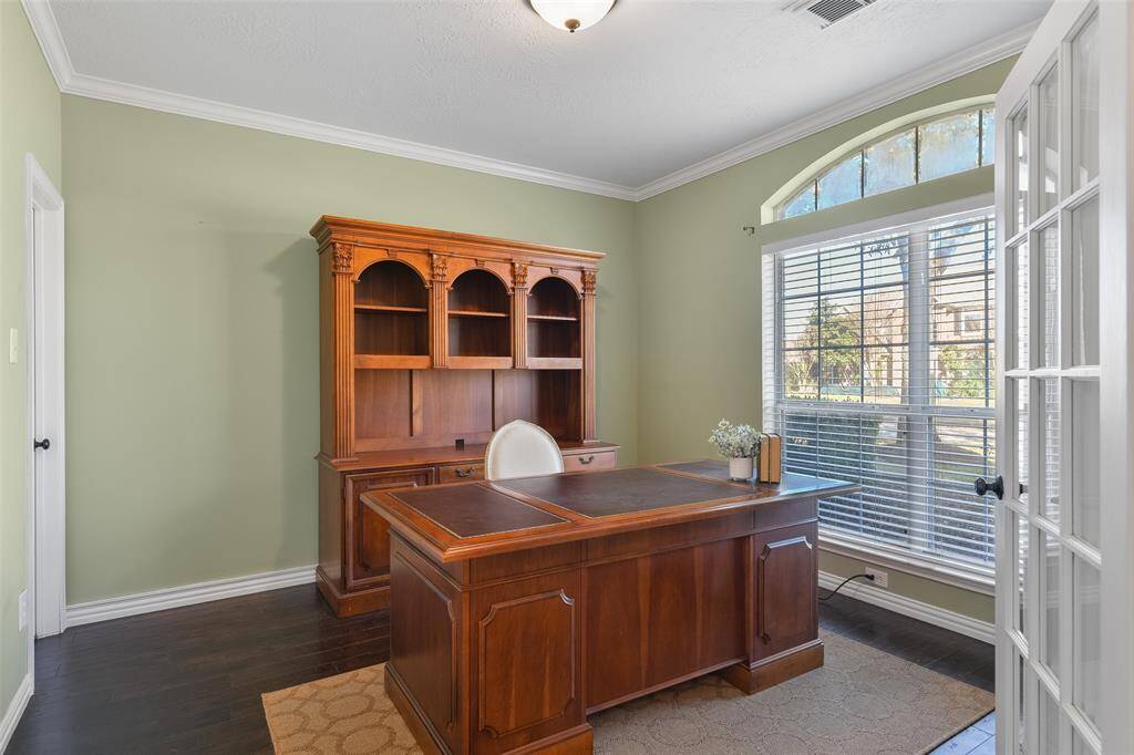 Returning to the front of the home, a pair of French doors open off of the left side of the foyer into this secluded study that offers custom paint, crown molding, engineered wood floors, a palladium arched window, a closet, and access to a full bathroom.