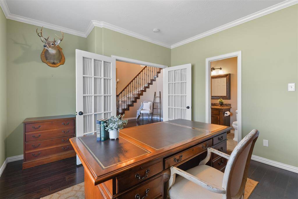 Returning to the front of the home, a pair of French doors open off of the left side of the foyer into this secluded study that offers custom paint, crown molding, engineered wood floors, a palladium arched window, a closet, and access to a full bathroom.