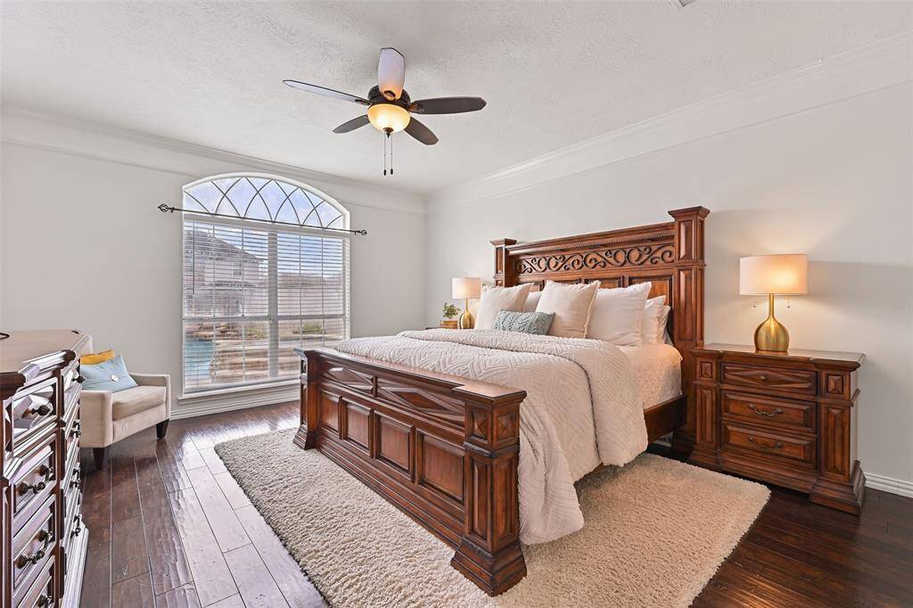 Escape to the serenity of this first-floor owners retreat complete with fresh white paint and oversized crown molding, continued engineered wood floors, a lighted ceiling fan, and a palladium arched window framing beautiful pool views.