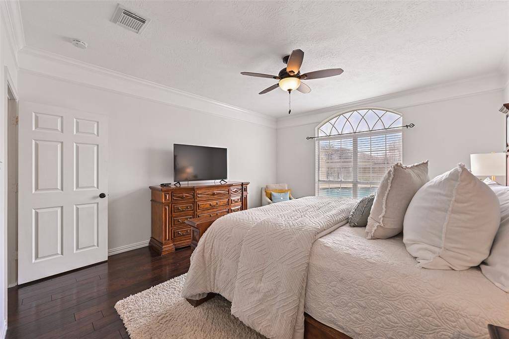 Escape to the serenity of this first-floor owners retreat complete with fresh white paint and oversized crown molding, continued engineered wood floors, a lighted ceiling fan, and a palladium arched window framing beautiful pool views.
