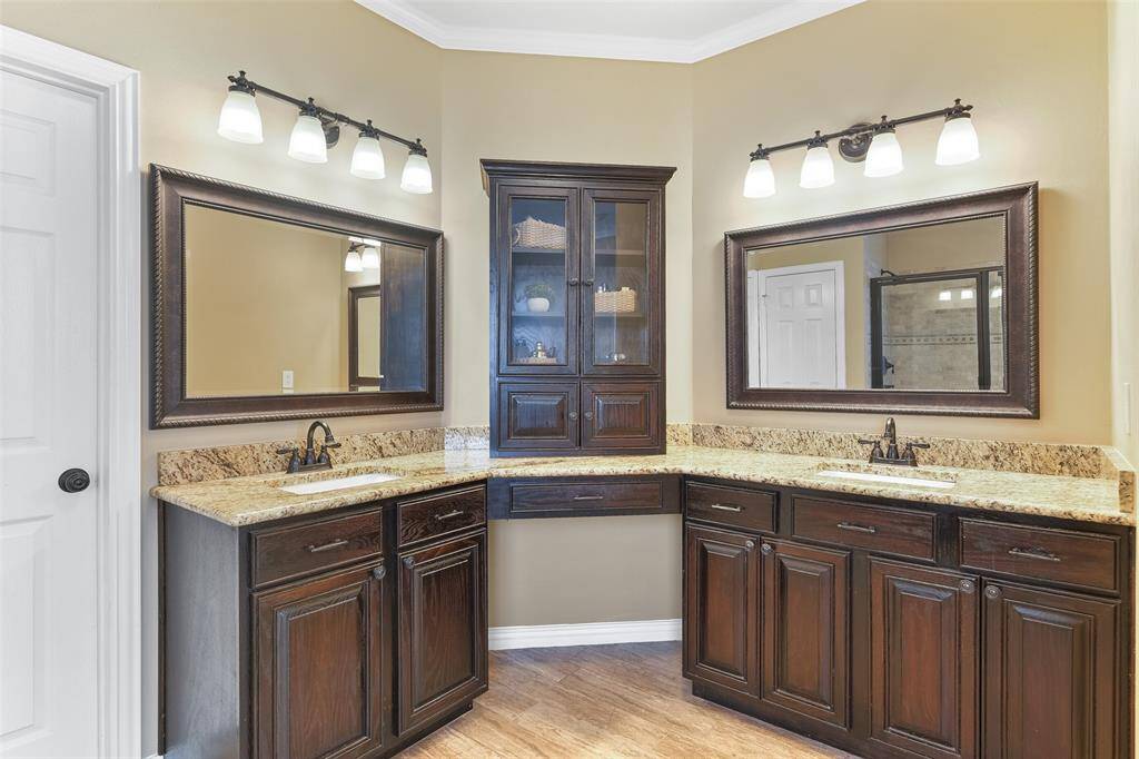 Step into the updated master bathroom and note the wrap-around vanity with granite countertops, separate his & hers undermount sinks, beautifully stained woodwork, wood-look tile floors, a soaking tub, and an oversized glass enclosed shower with a bench seat & a travertine tile surround.