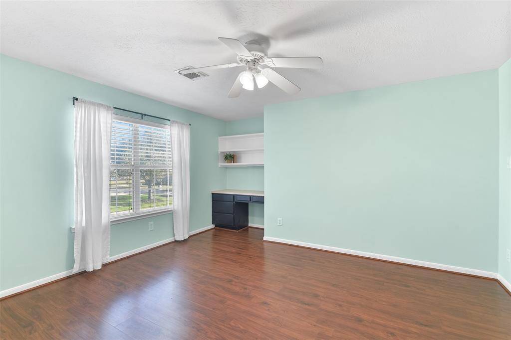 The fourth and final bedroom in the home is also located on the second floor and it offers the same paint as the previous bedroom, an all-white lighted ceiling fan, a sunlit window with 2-inch binds and breezy draperies, and a built-in desk station in the alcove.