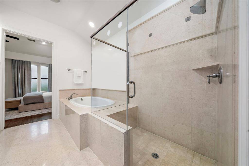 A frameless walk-in shower and oversized tub offer spa-like amenities, with a clear sightline back to the bedroom that enhances the suite’s connected flow and privacy.