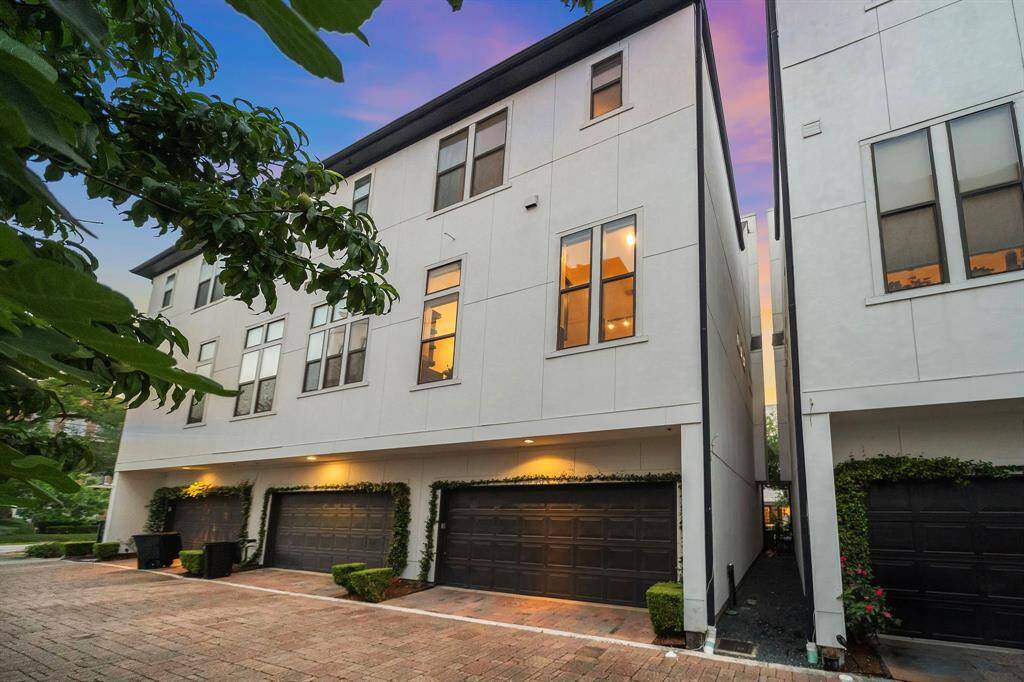 The rear elevation includes an attached two-car garage with a shared driveway and low-maintenance landscaping. Major exterior updates include a new roof installed in 2024 (30-year warranty) and zoned HVAC enhancements completed between 2022–2024.
