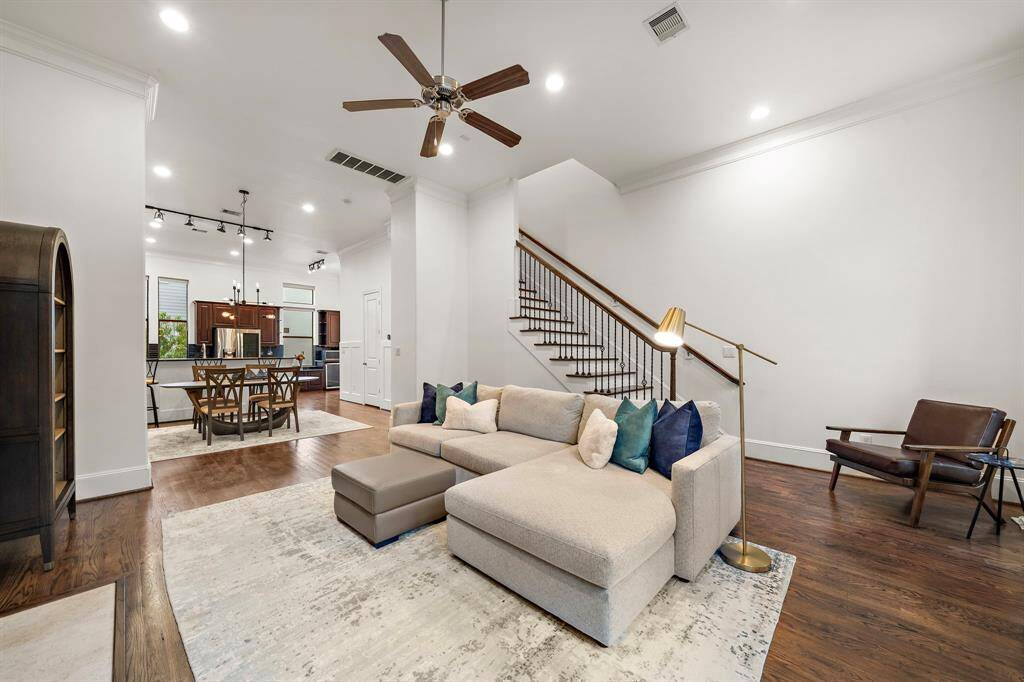 This main living space is framed by detailed crown molding and elegant wood railings, offering a natural gathering zone that ties the entire first floor together.