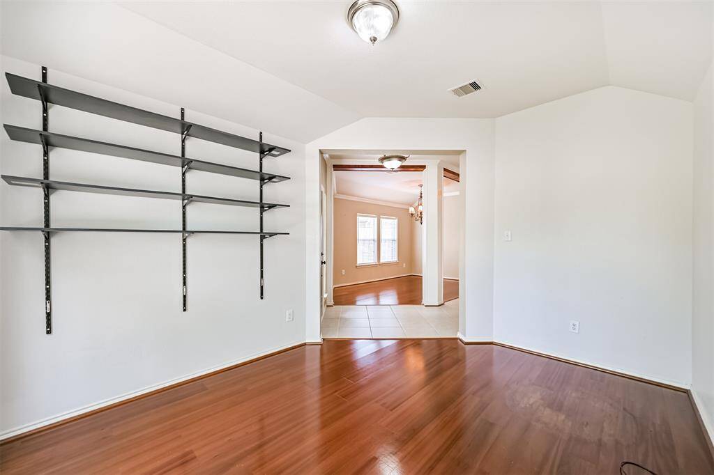 This inviting  office space features elegant wood flooring, built-in shelving,