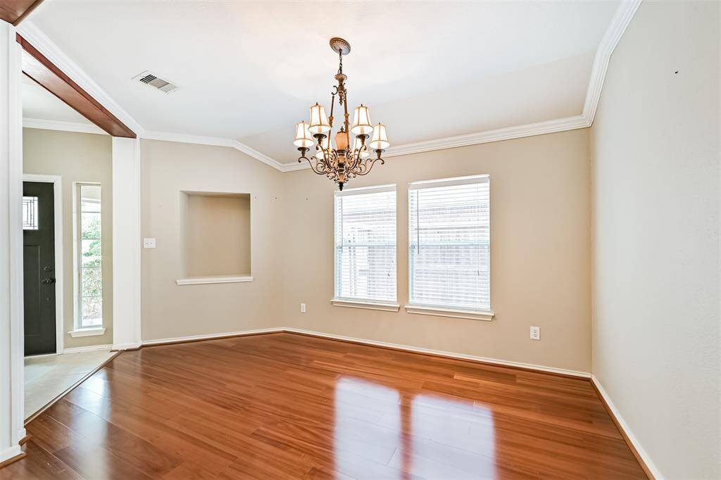 Bright dining room with large windows, hardwood floors, and crown molding. Features a built-in shelving nook chandelier and access door to the outside.