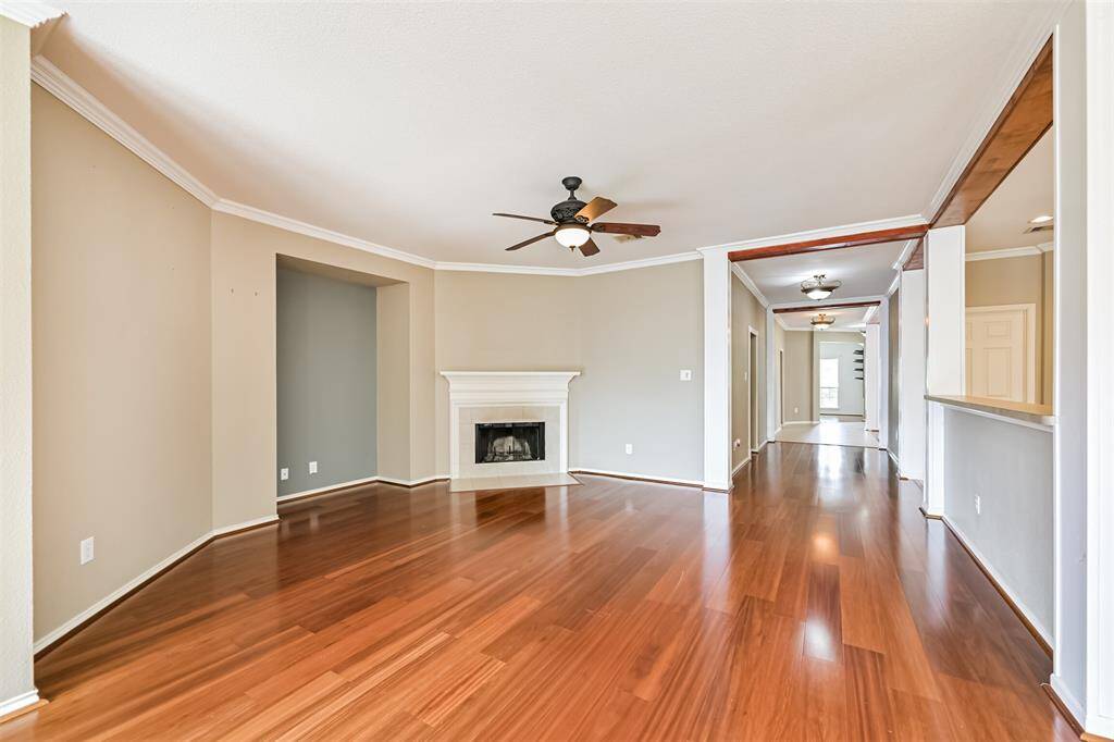 The livingroom showcases a spacious open-concept living area with hardwood flooring, a cozy fireplace, and ceiling fans.