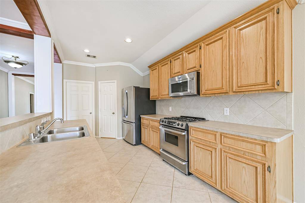 Bright kitchen featuring wooden cabinets, a modern gas stove with built-in microwave, and a tiled backsplash.