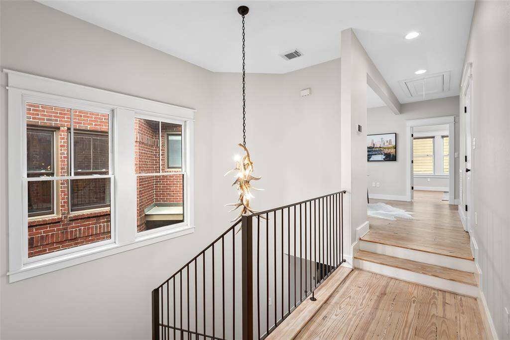 [Stairs/ 2nd story landing]  Modern wrought iron railing, and rustic chandelier compliment the transitional design