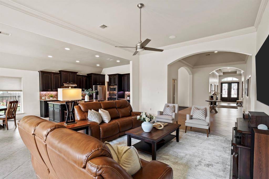 This spacious family room offers seamless flow into the kitchen and foyer, highlighted by elegant crown molding, arched walkways, and stylish recessed lighting.