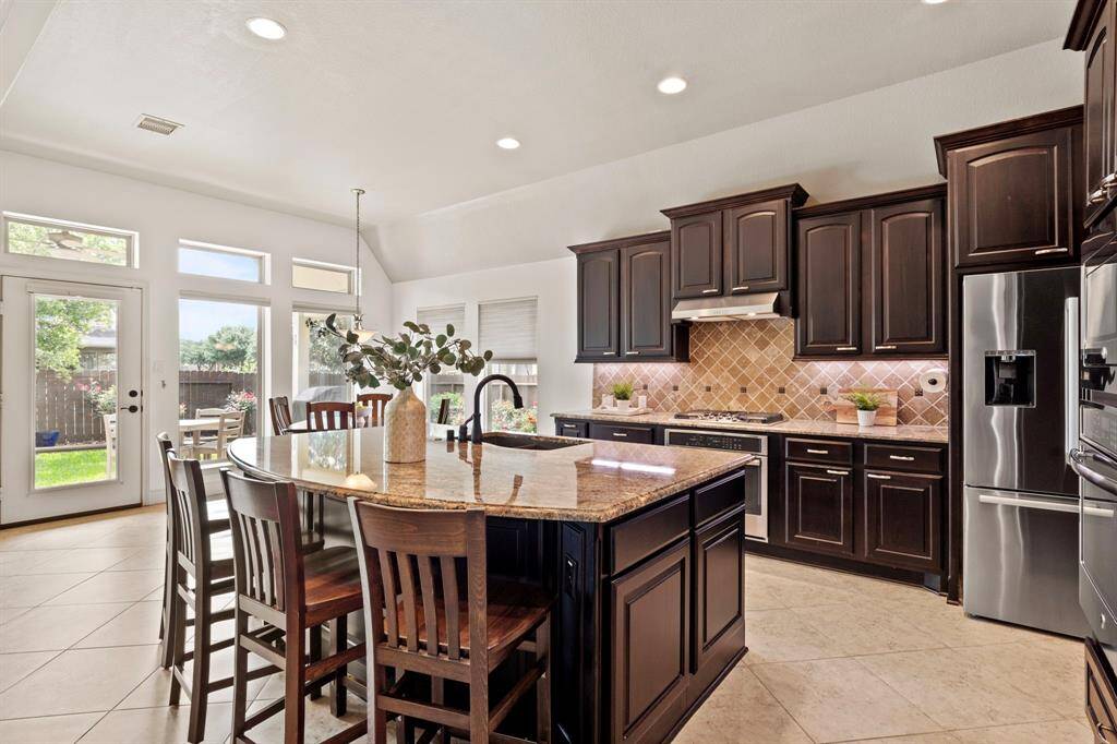 A spacious island with curved breakfast bar seating anchors the kitchen, perfect for casual dining or entertaining while cooking.