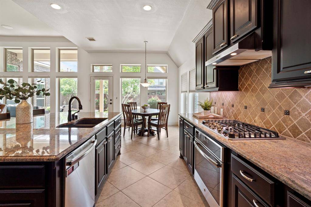 Enjoy scenic backyard views from the heart of the kitchen and breakfast area through walls of windows and a full-glass door leading to the patio.