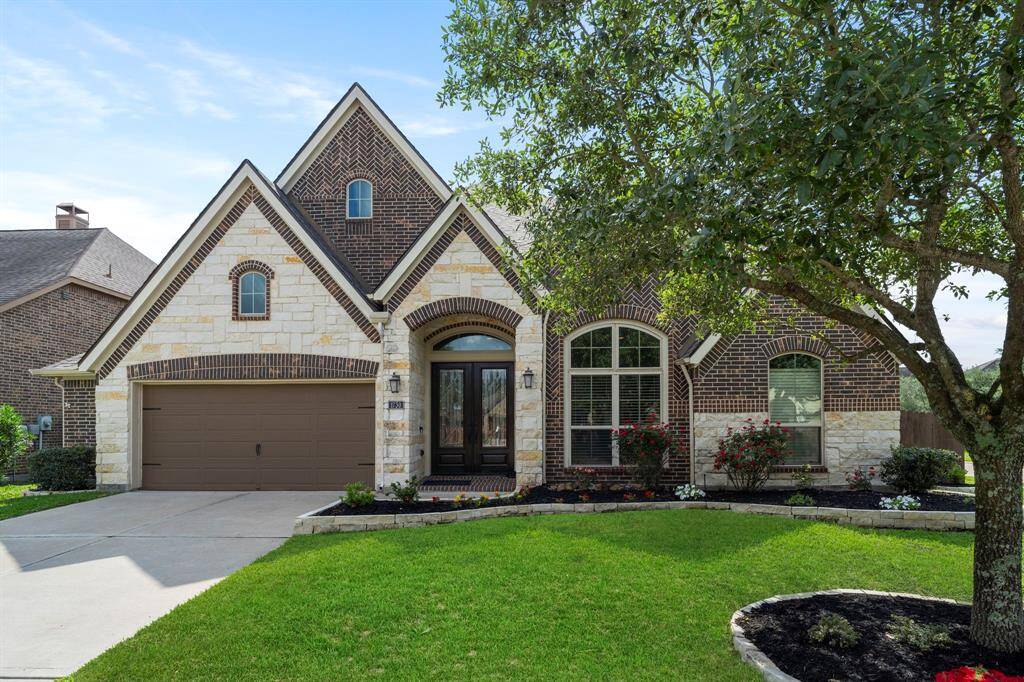 With a rich blend of stone and dark brick, this home's timeless façade and lush landscaping make a lasting impression under clear Texas skies.