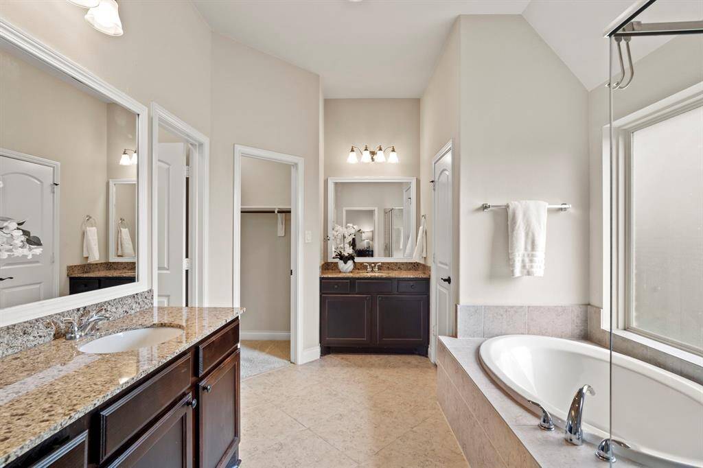 The ensuite bathroom features dual vanities with granite countertops, and dual walk-in closets, all under high ceilings that enhance the sense of space.