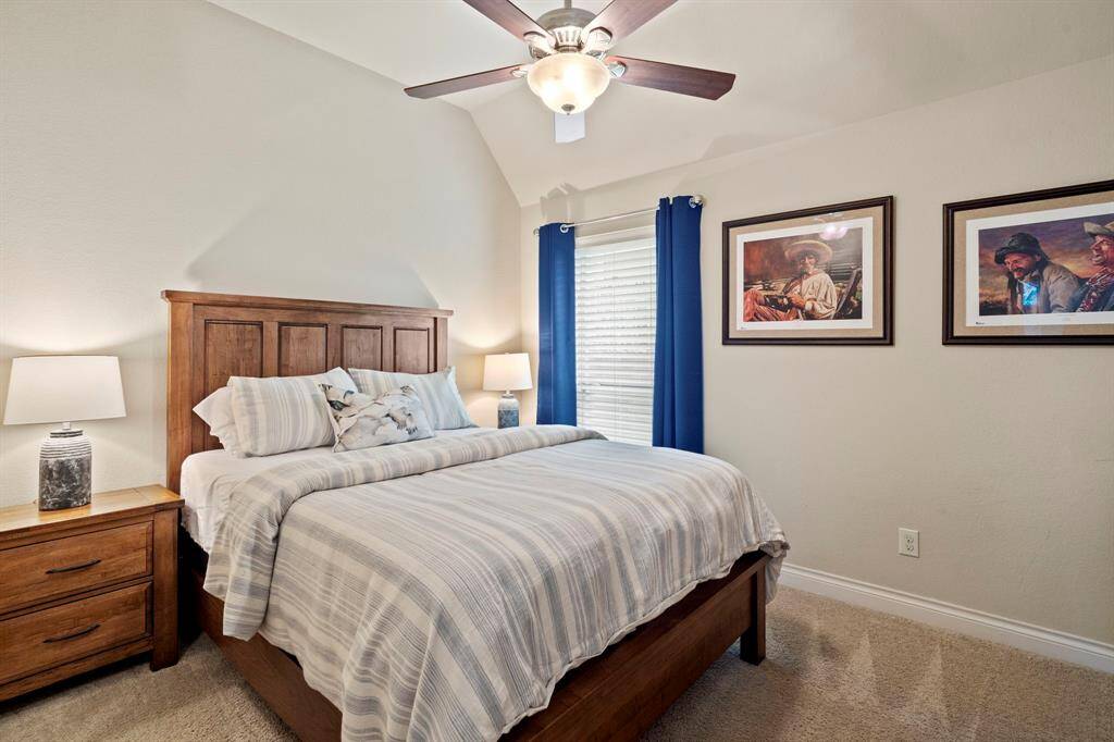This guest suite features plush carpet, a cooling fan, and large windows with custom drapery, creating a peaceful retreat for visitors.