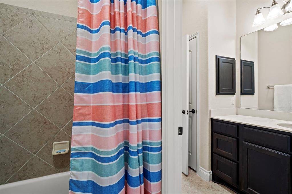 The shared bathroom includes a flexible tub/shower combo tucked between privacy doors, ideal for guests or family members.
