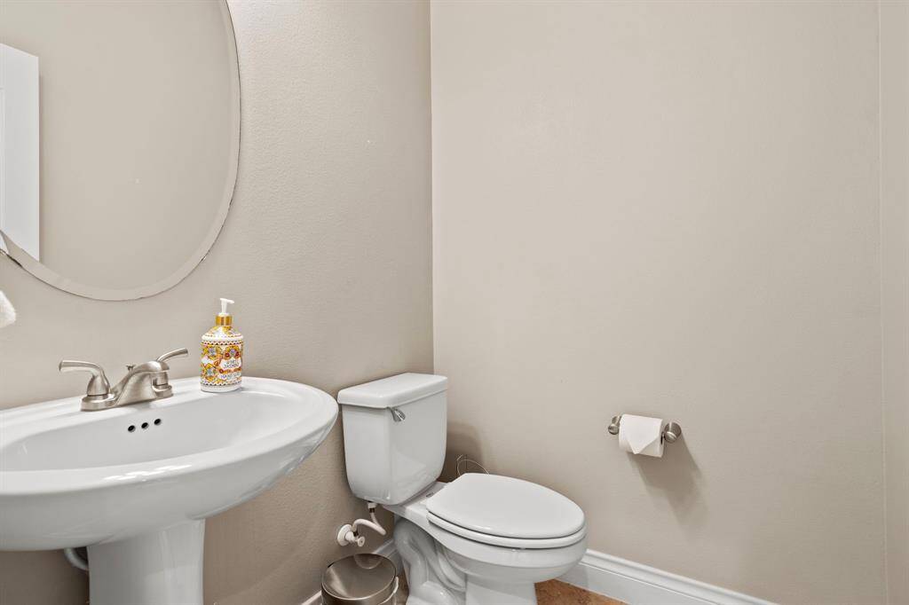 Conveniently located for guests, this powder bath features a pedestal sink, sleek fixtures, and neutral tones for a clean and classic look.