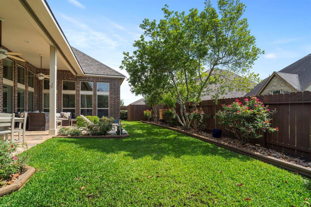 Manicured flower beds and mature trees line the fully fenced backyard, creating a beautiful and private backdrop for outdoor enjoyment.
