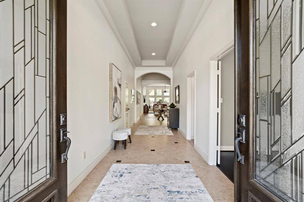 Step inside to a grand entryway with soaring ceilings, elegant crown molding, and a long, light-filled hallway that offers a stunning preview of the home’s open design and stylish finishes.