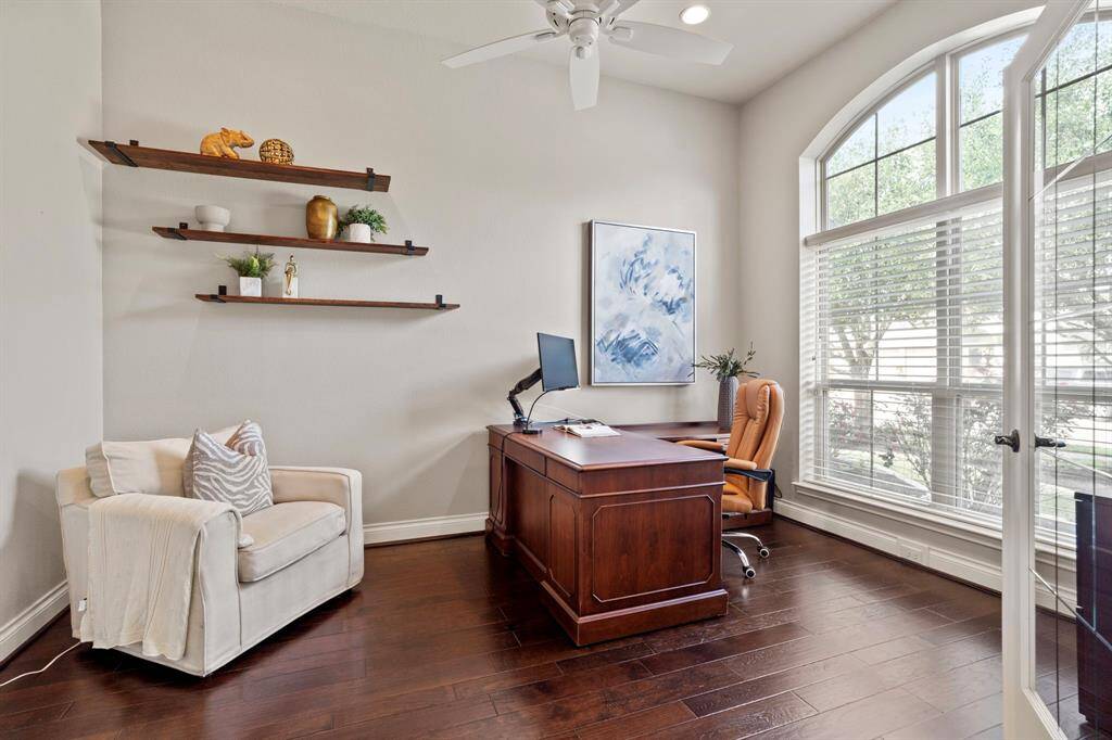 A wall of windows fills the study with natural light, while the arched transom and crisp finishes create a serene environment perfect for productivity or quiet reading.