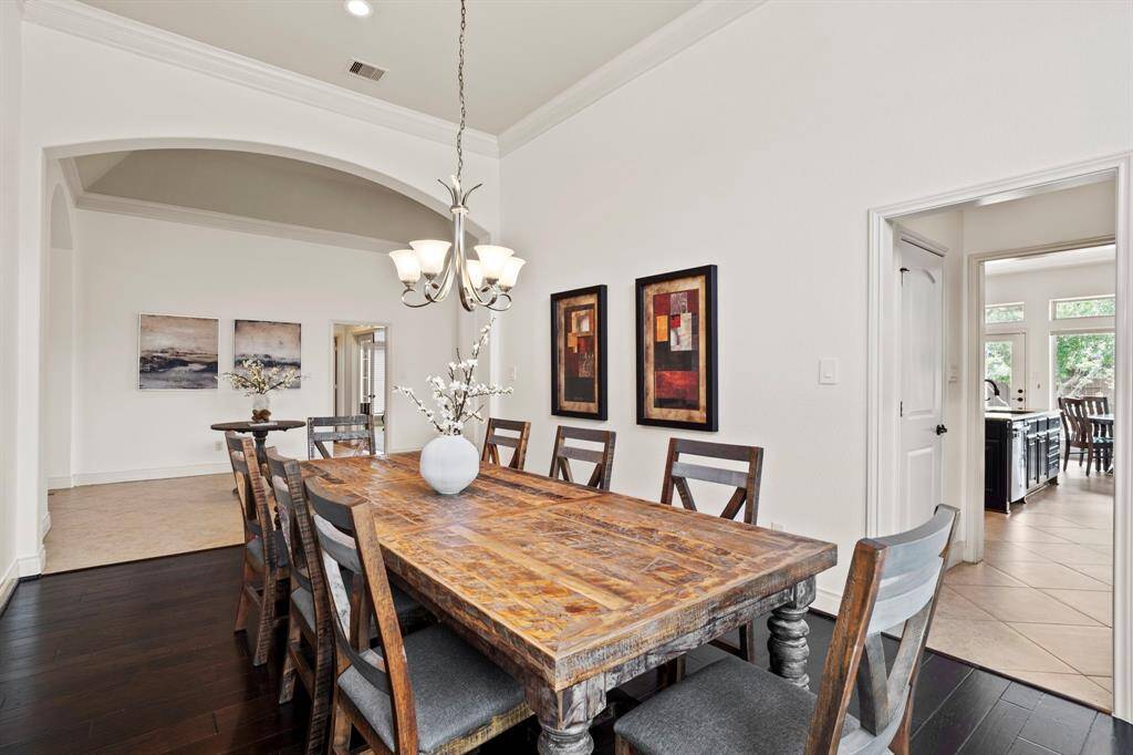 The formal dining room is framed by a dramatic arched entry and features rich wood flooring, crown molding, and easy access to the kitchen for effortless hosting.
