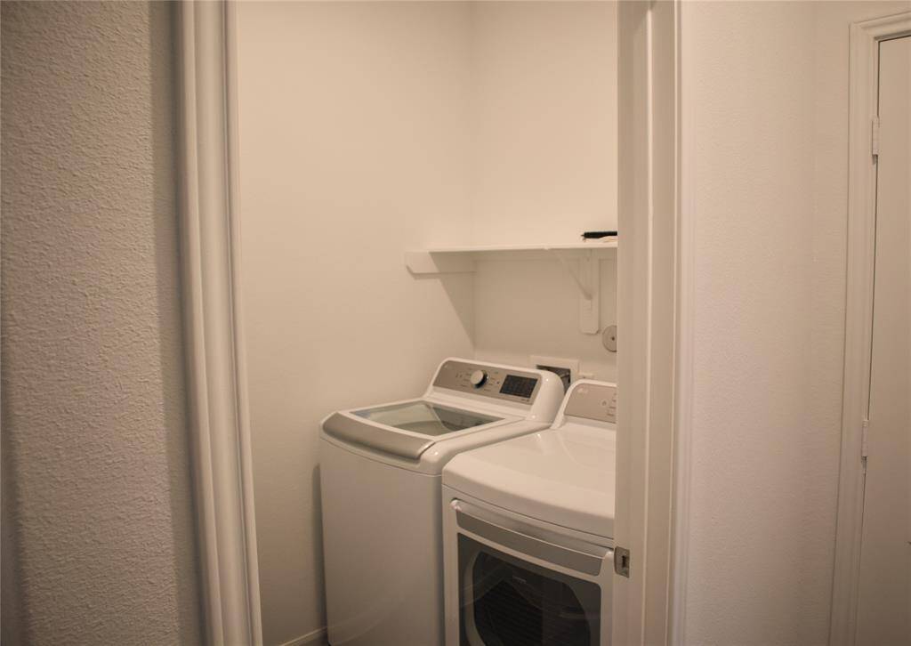 Laundry room is equipped with a washer, dryer and shelf space.