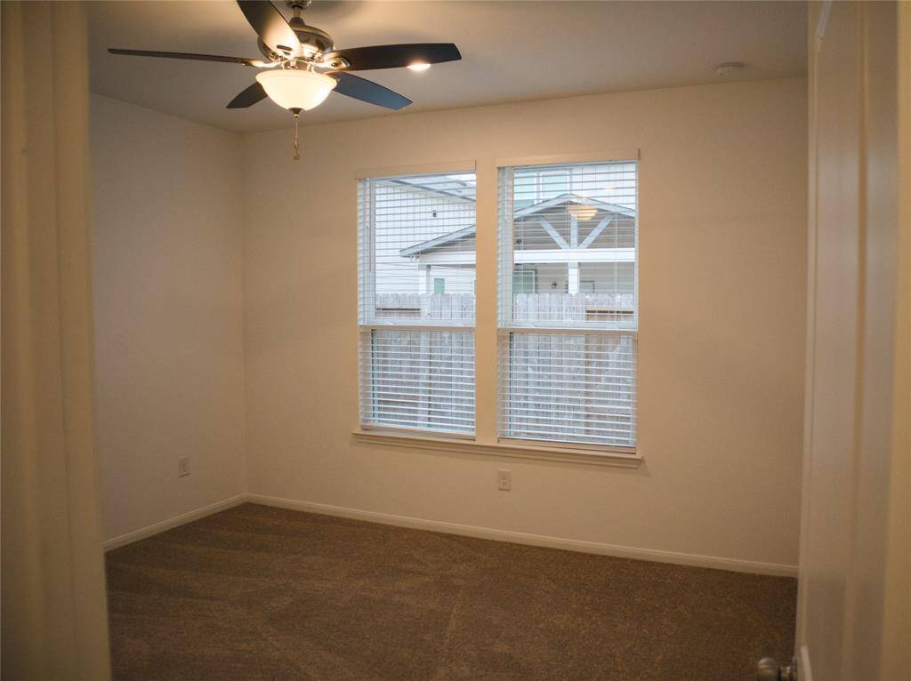 Primary suite at the back of the home features new carpet, paint and a ceiling fan