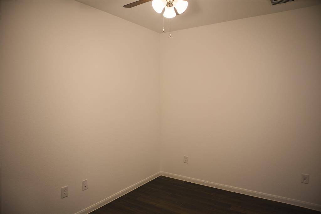 Office space is equipped with wood like flooring and a ceiling fan with light