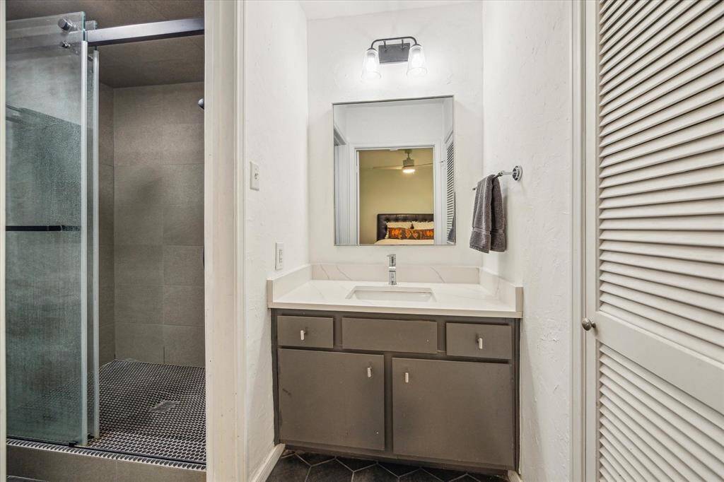 The bathroom features a large updated shower, under sink storage and a linen closet.