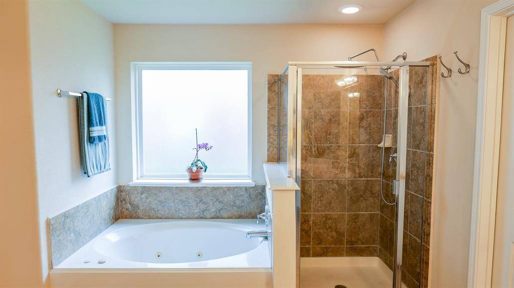 There is a tiled shower and jetted tub with a frosted window allowing natural light as you get ready for the day.