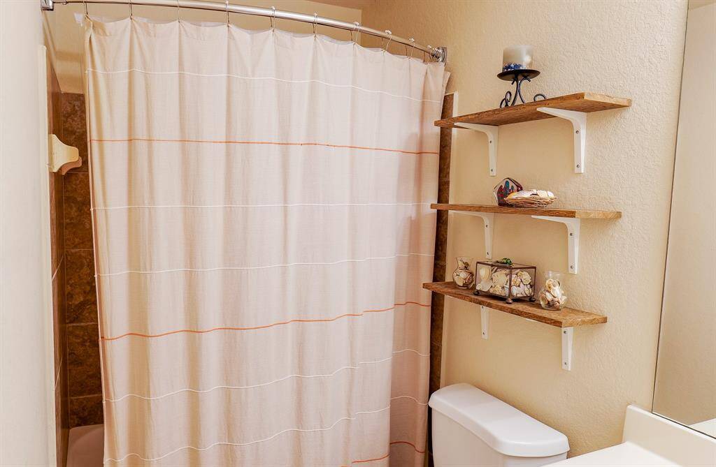 The secondary bathroom has a tiled tub area and is located next to the bedrooms.