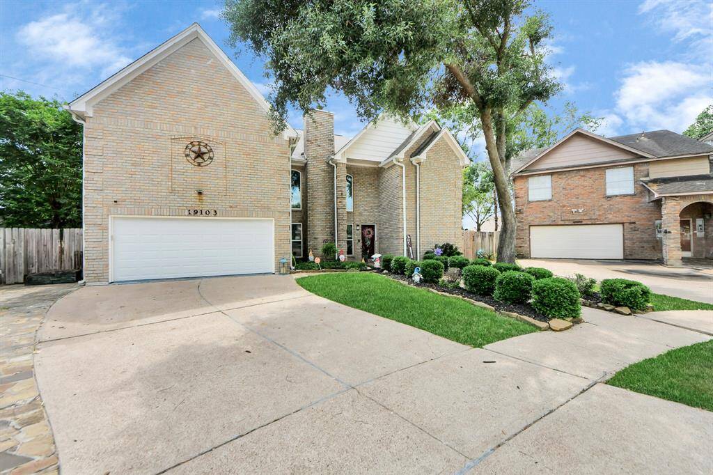 The property includes a spacious driveway leading to a two-car garage, and the exterior has a welcoming and elegant appearance.