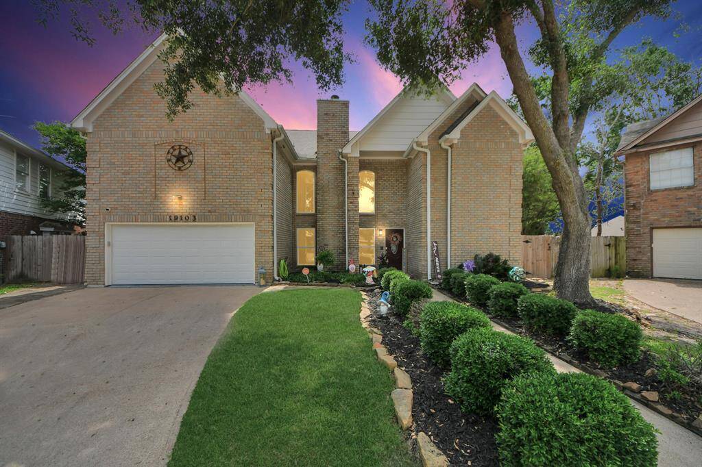 A charming two-story brick home with a well-maintained front yard and landscaping. It features a two-car garage, large windows, and a welcoming entryway. The vibrant sky adds to the home's curb appeal.
