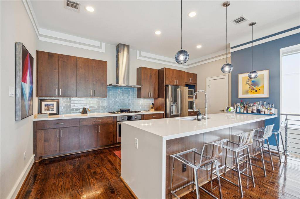 Chefs dream kitchen with huge peninsula with breakfast bar. Notice the designer pendant lighting and attractive glass backsplash.