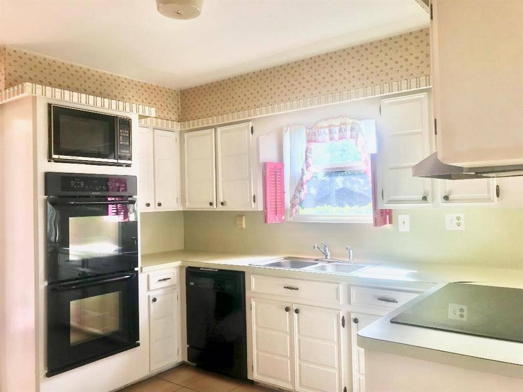Closer view of the kitchen with updated double ovens and microwave and dishwasher