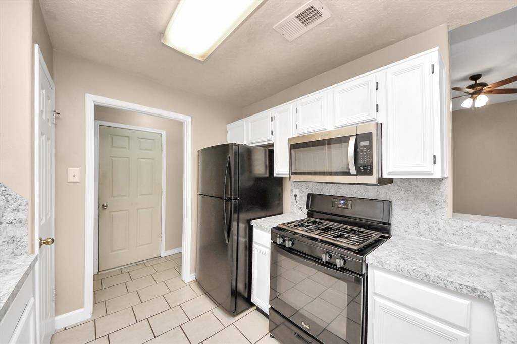 Compact kitchen with modern appliances, including a black refrigerator and gas stove.