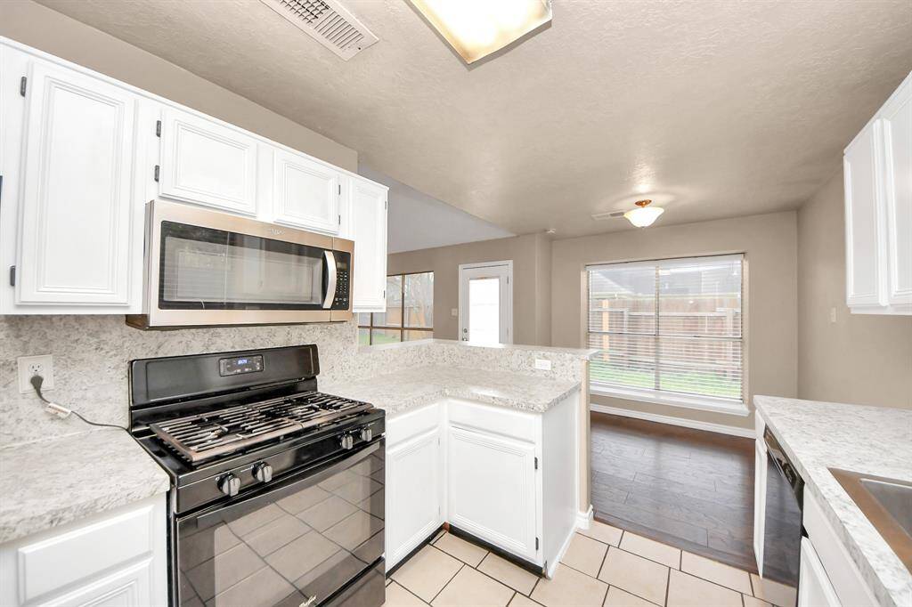 The kitchen space opens to a bright dining area with a large window and a view of the backyard.