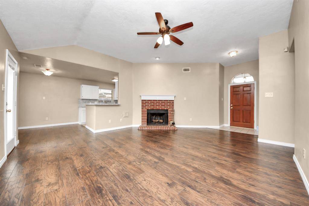 The room flows into an open kitchen with a breakfast bar, while a warm, inviting front door welcomes you home.