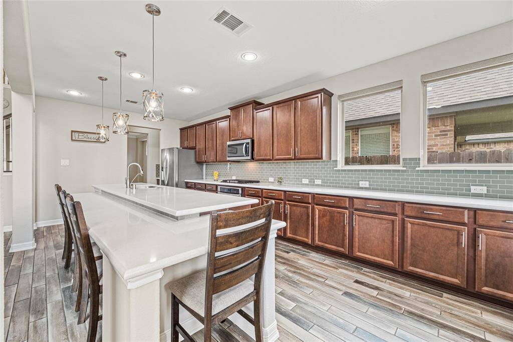 Your chef-inspired kitchen is ready to impress! This beautifully designed space with gleaming quartz countertops, a coordinating styled backsplash, and sleek stainless steel appliances. Enhanced with updated hardware, is perfectly complemented by pendent lighting. At the heart of it all, a sprawling island with breakfast bar seating offering the perfect spot for casual dining and entertaining.