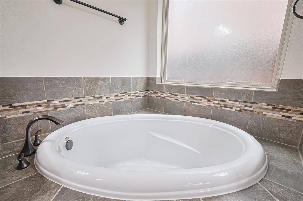 Primary bathroom presents double sinks, water closet, bathtub and separate shower