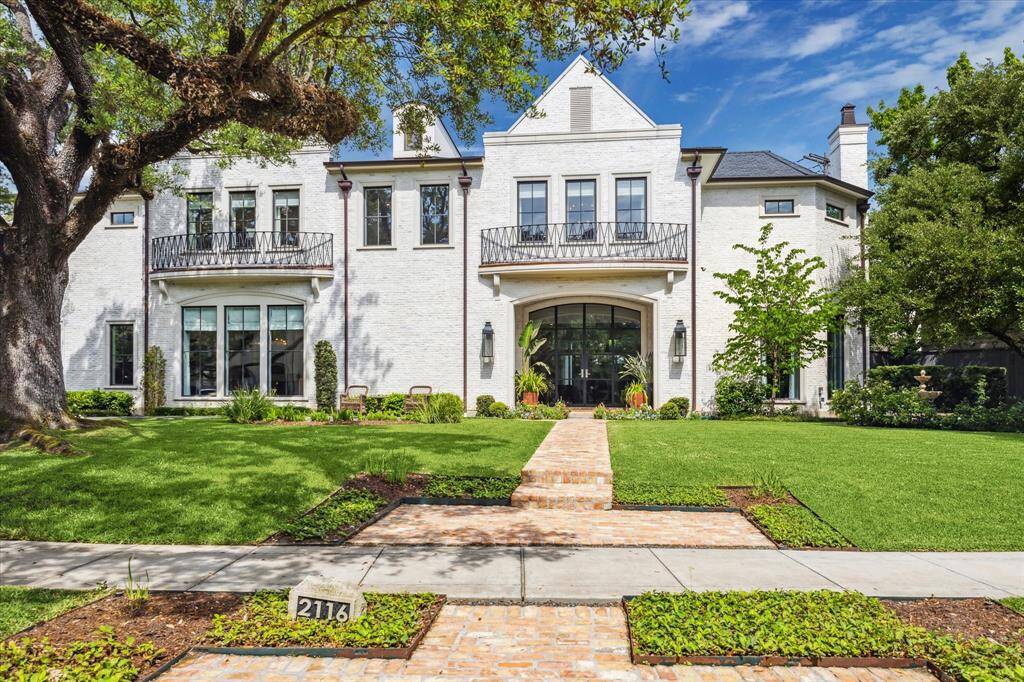 2116 Looscan welcomes you with with lush landscaping and stately oak trees. This stunning traditional brick home was designed by Preston Wood and built by Charter Custom Homes in 2020. Situated on an almost 16,000 square foot lot, the home's exterior is enhanced by a slate tile roof, metalwork balcony rails, gas lanterns, and copper gutters.