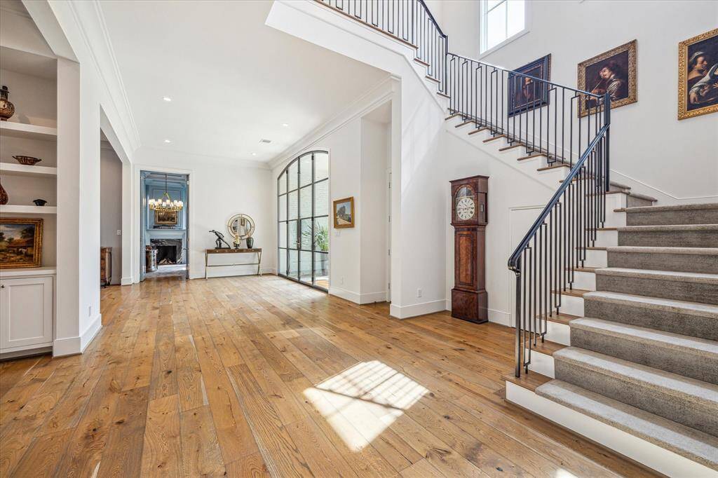 This stunning home offers the perfect blend of contemporary finishes and features alongside traditional River Oaks elegance. The custom steel and glass front doors bring an abundance of light into this welcoming central hallway. The library is straight ahead through the doorway, with the living room through the first cased opening. The family room is directly across from the stairway landing.