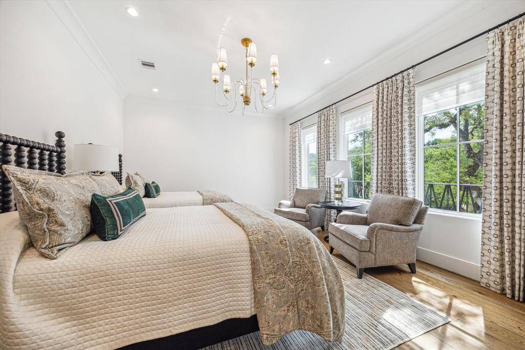 This refined bedroom easily accommodates two queen size beds and overlooks the front yard of the home.